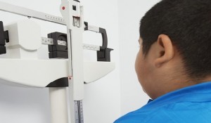 Obese boy measuring weight on scales in clinic